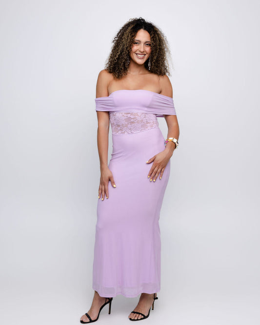 A woman modeling an off-the-shoulder lavender maxi dress with a lace-trimmed waist, paired with black high-heeled sandals, against a light gray studio background.