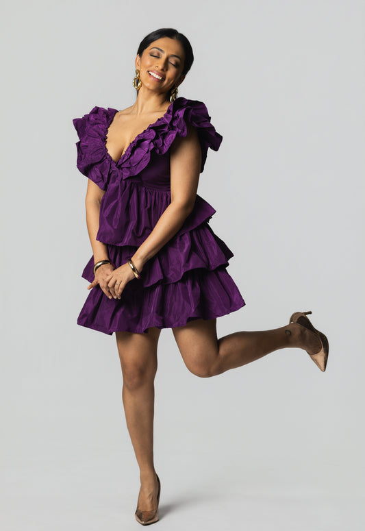 Woman wearing a purple dress posing against a gray background